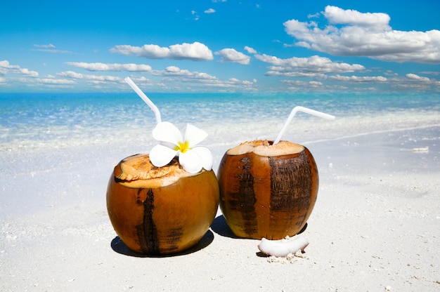 Due cocktail di cocco sulla spiaggia di sabbia bianca accanto all'acqua di mare pulita. Concetto di vacanze e viaggi