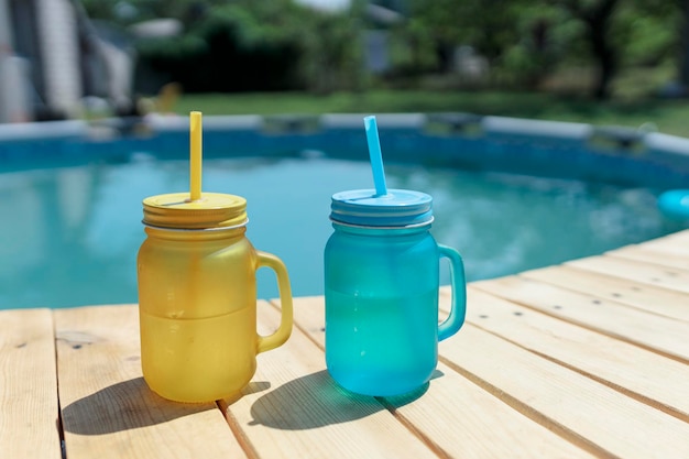Due cocktail di giallo e blu in piedi a bordo piscina Festa in piscina all'aperto