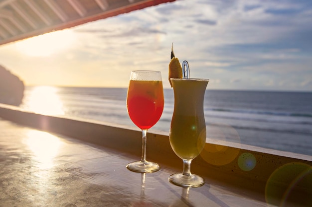 Due cocktail Pina Colada e Tequila Sunrise al bar della spiaggia con vista mare al tramonto, Bali