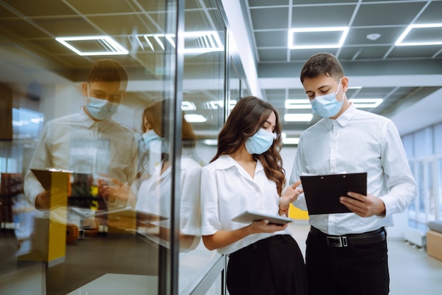 Due colleghi con maschere protettive in un ufficio moderno discutono insieme di problemi di lavoro.