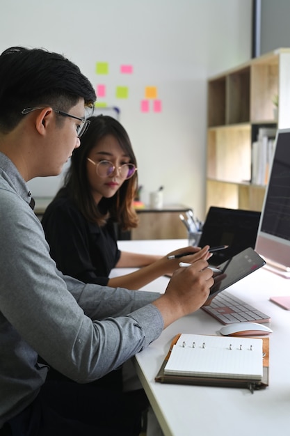 Due colleghi di lavoro che analizzano insieme il grafico finanziario sulla tavoletta digitale.