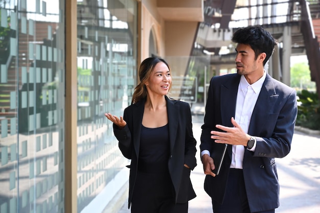 Due colleghi di lavoro di successo che discutono mentre camminano fuori dall'edificio per uffici moderno