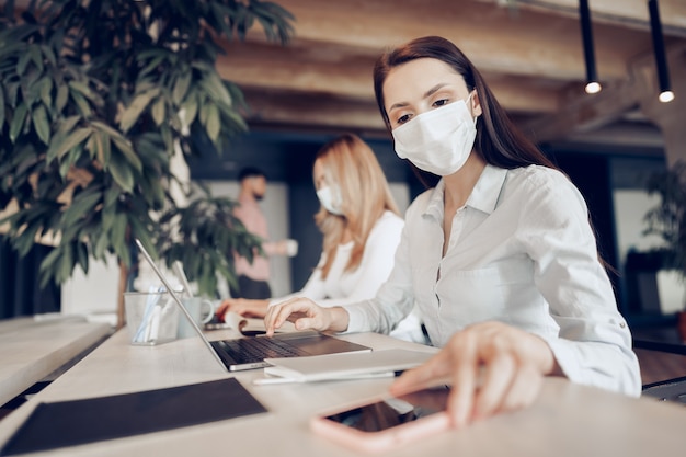 Due colleghi di sesso femminile che lavorano in ufficio insieme indossando maschere mediche