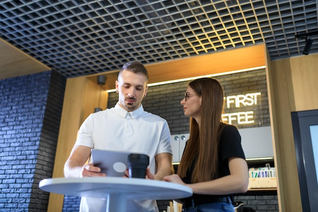 Due colleghi lavorano durante una pausa caffè con un tablet