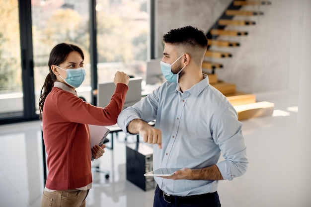 Due colleghi salutano con i gomiti in ufficio a causa della pandemia di COVID19