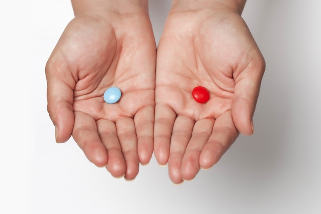 Due compresse rosse e blu tra cui scegliere sui palmi con spazio per il testo su sfondo bianco