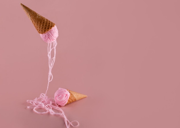 Due coni di cialda con filato rosa invece del concetto di hobby del gelato su sfondo rosa