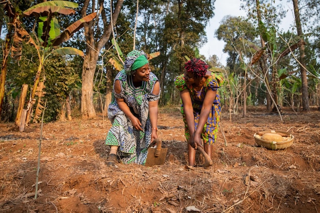 Due contadine zappano felicemente i campi in Africa donne e agricoltura