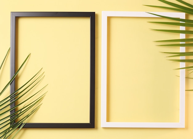 Due cornici fotografiche e foglie di palma su sfondo giallo pastello