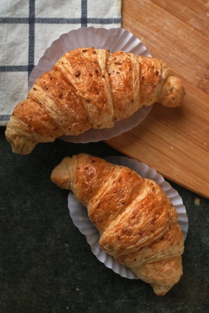 Due croissant su un tavolo con un tagliere di legno.