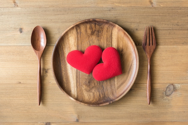 due cuore rosso in un piatto di legno