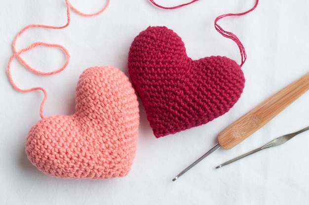 Due cuori rosa amigurumi all'uncinetto con ganci a crochet su sfondo bianco Banner di San Valentino vista dall'alto