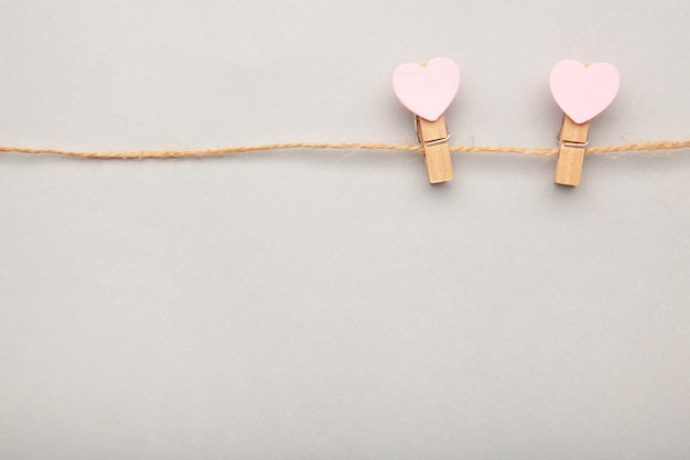 Due cuori rosa delle mollette da bucato che appendono sulla corda su gray