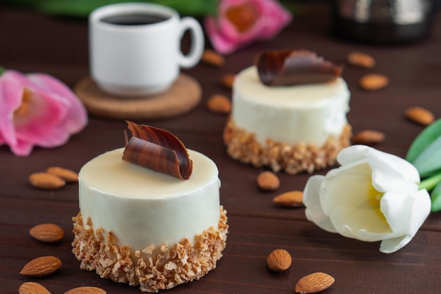 Due cupcakes con cioccolato bianco tazza di caffè mandorla e tulipani su tavola di legno Messa a fuoco selettiva