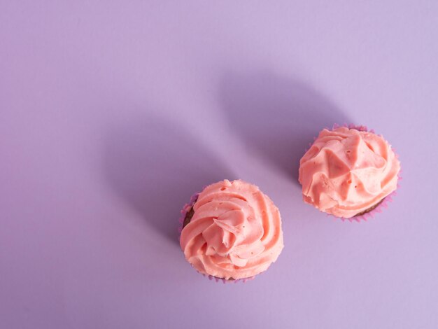 Due cupcakes su uno sfondo viola con una vista dall'alto di crema rosa