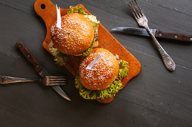 Due deliziosi e deliziosi hamburger fatti in casa usati per tagliare la carne. sul tavolo di legno.