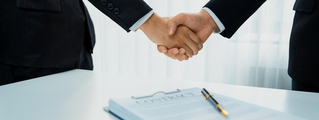 Due dirigenti aziendali stringono la mano nella sala del consiglio per siglare l'accordo di fusione di due società La stretta di mano simboleggia la partnership aziendale e la cooperazione Il concetto di acquisizione e fusione aziendale