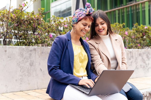 Due donne adulte latine che esaminano il computer portatile