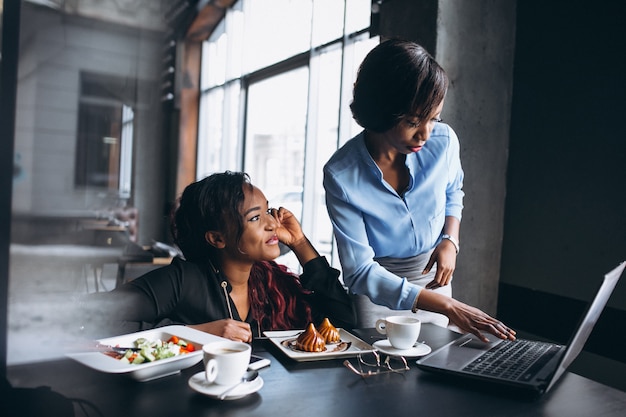 Due donne afroamericane con laptop e pranzo