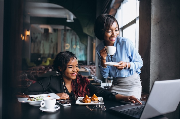 Due donne afroamericane con laptop e pranzo