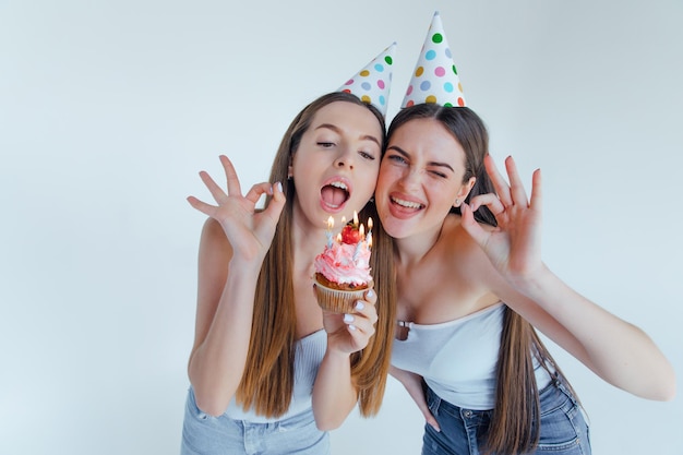 Due donne amici vestiti europei cappelli di compleanno in posa. Concetto di stile di vita delle persone.