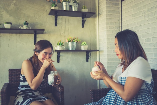 Due donne asiatiche che parlano della storia dello scherzo nel concetto felice della donna incinta del negozio di caffè