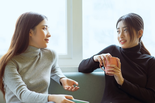 Due donne asiatiche chiacchierano vicino alla finestra