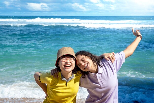 Due donne asiatiche con un'espressione eccitata che viaggiano sulla spiaggia