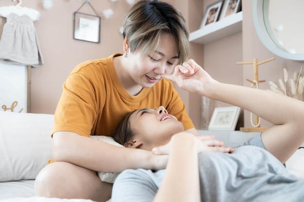 Due donne asiatiche lgbtq lesbiche omosessuali Lesbiche coppie sdraiate sul letto e guardando insieme sorridere e rilassarsi a casa Donna asiatica LGBTQLGBTLGBTQ amore sul letto bianco e testa insieme