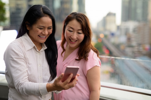 Due donne asiatiche mature insieme contro la vista della città