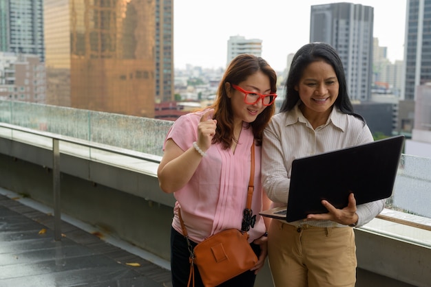 Due donne asiatiche mature insieme contro la vista della città