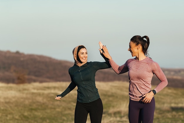 Due donne atletiche che si sostengono a vicenda mentre fanno jogging e danno il cinque in natura