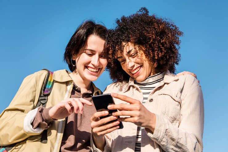 Due donne che godono di immagini divertenti sul telefono