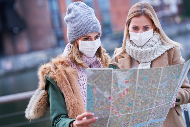 due donne che indossano maschere e tengono in mano una mappa mentre visitano Danzica in Polonia