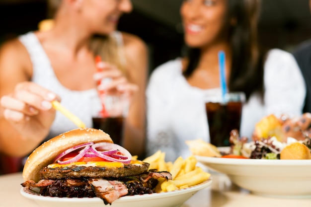 Due donne che mangiano hamburger e bevono soda