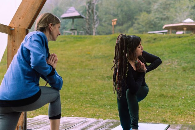 Due donne che praticano yoga nella foresta.