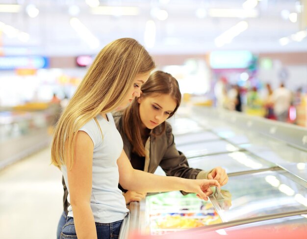 Due donne che scelgono alimenti congelati da un congelatore del supermercato