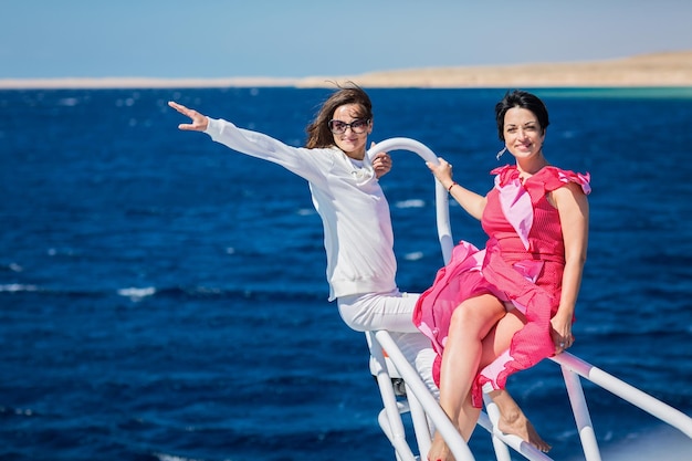 Due donne che si rilassano insieme sul muso dello yacht in una soleggiata giornata estiva in mare