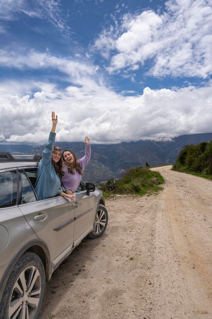 Due donne che sporgono dal finestrino di un'auto mentre salutano con la mano la nostra porta