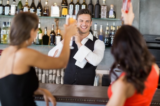 Due donne che tostano i bicchieri al bancone del bar