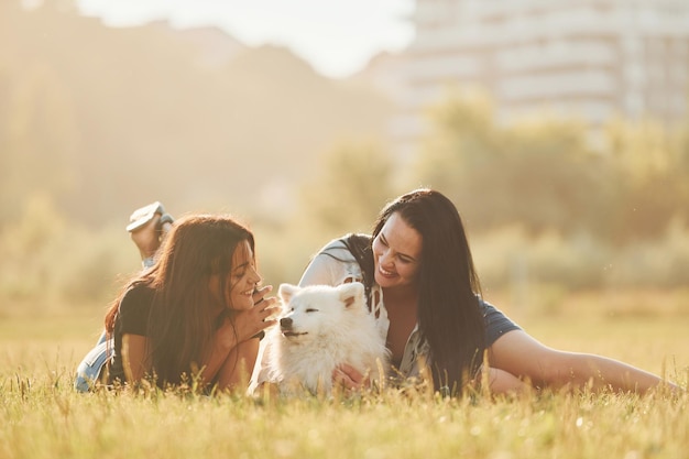 Due donne con il cane si divertono sul campo durante la giornata di sole
