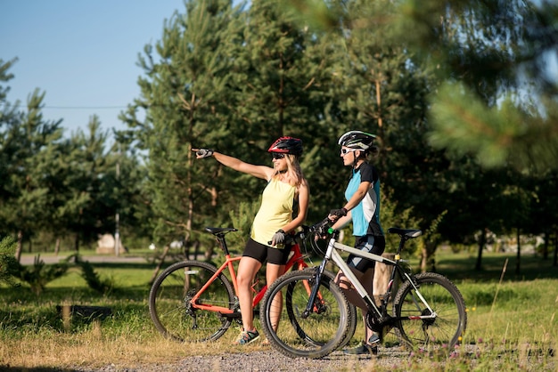 Due donne con le biciclette si sono fermate e conversano all'aperto nel parco