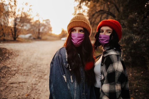 Due donne con maschere mediche che propongono insieme