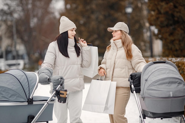 Due donne con passeggini che camminano insieme per la città e parlano