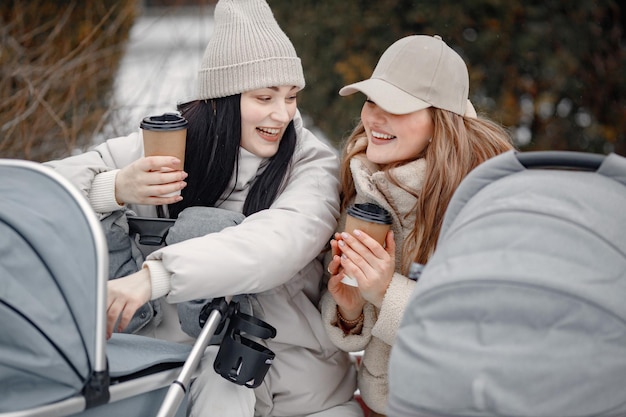 Due donne con passeggini seduti su una panchina e parlando