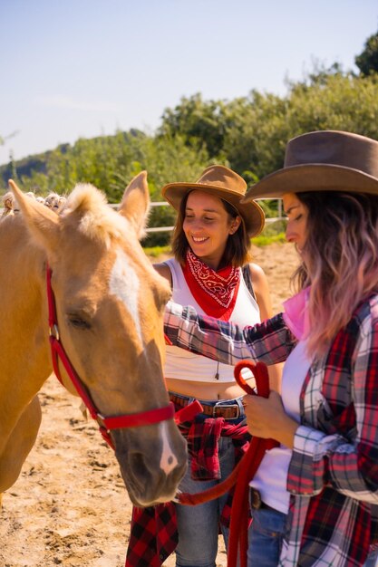 Due donne cowgirl accarezzano un cavallo a cavallo, con abiti sudamericani