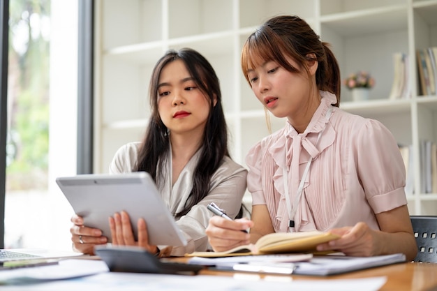 Due donne d'affari asiatiche professioniste stanno guardando lo schermo di un tablet e stanno lavorando a un progetto