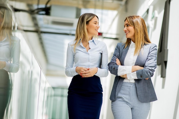 Due donne d'affari piuttosto giovani che camminano e discutono nel corridoio dell'ufficio