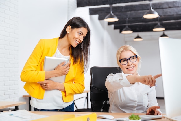 Due donne dell'ufficio abbastanza giovani e mature che hanno una riunione di brainstorming al tavolo in ufficio