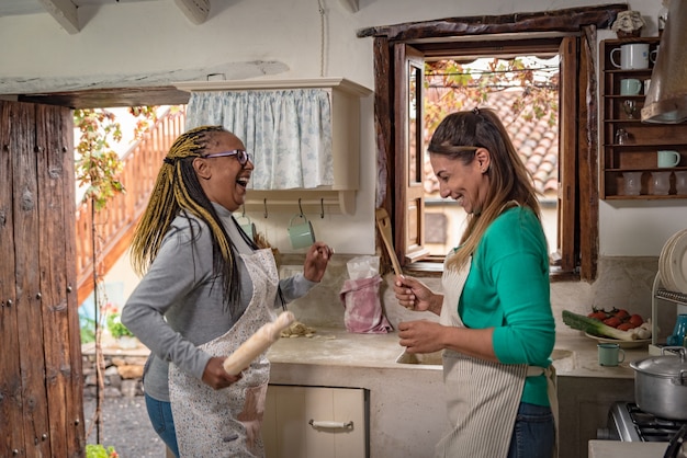 Due donne di razze diverse ballano mentre cucinano in una cucina vintage